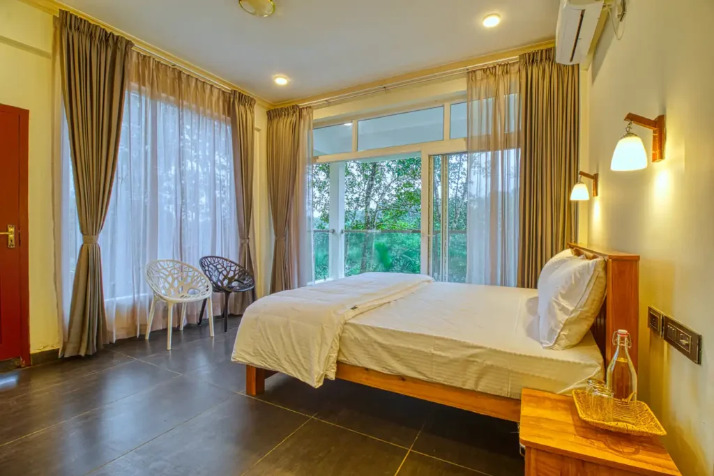 Forest-view suite room with king-size bed and large windows at Ende Wayanad Resort, Wayanad